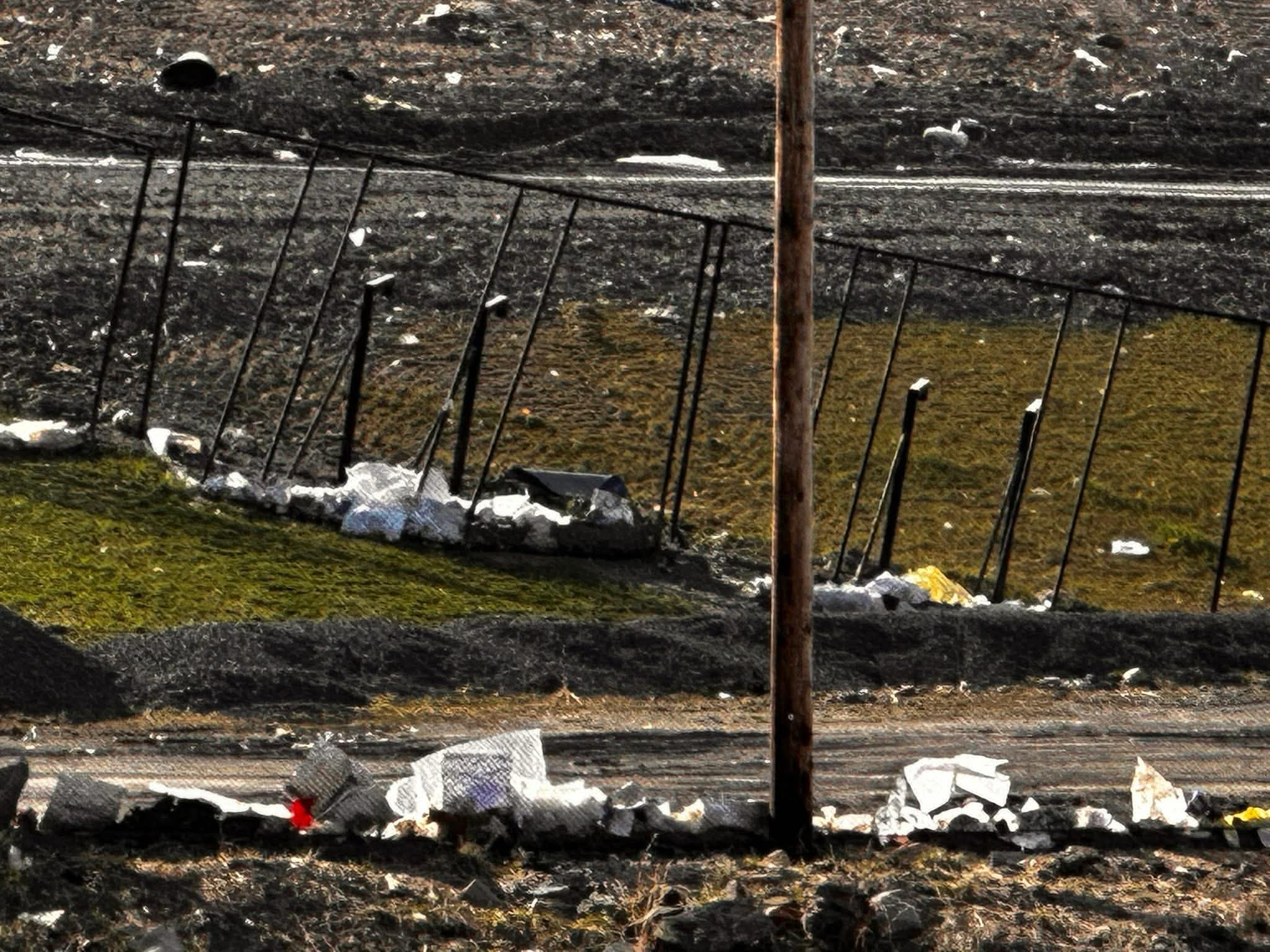 Close view of a sagging chain-link perimeter fence with caught litter along an active landfill berm.