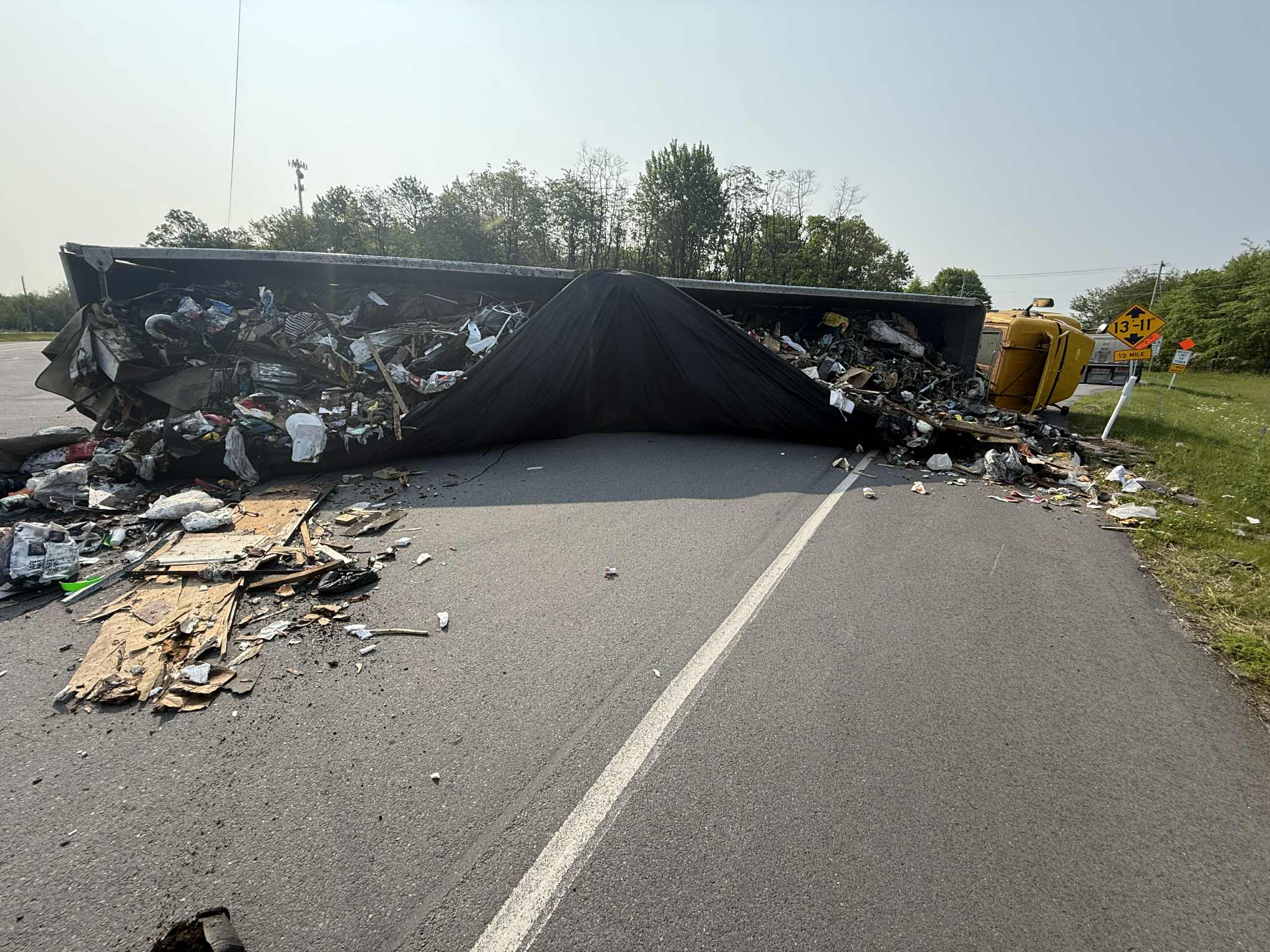 An overturned waste truck on a Schuylkill County road, cargo spilled across both lanes.